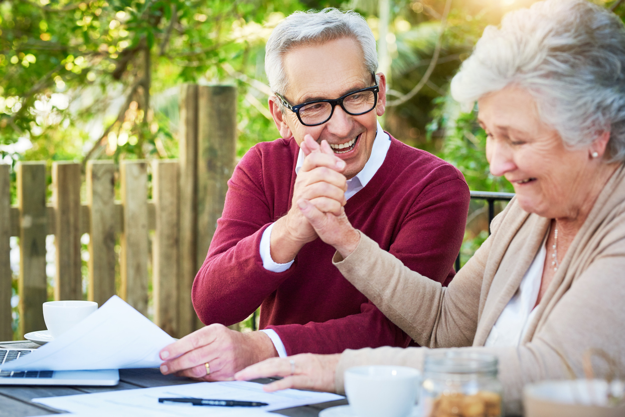 Shot of a senior couple high fiving while going over their finances while sitting outside