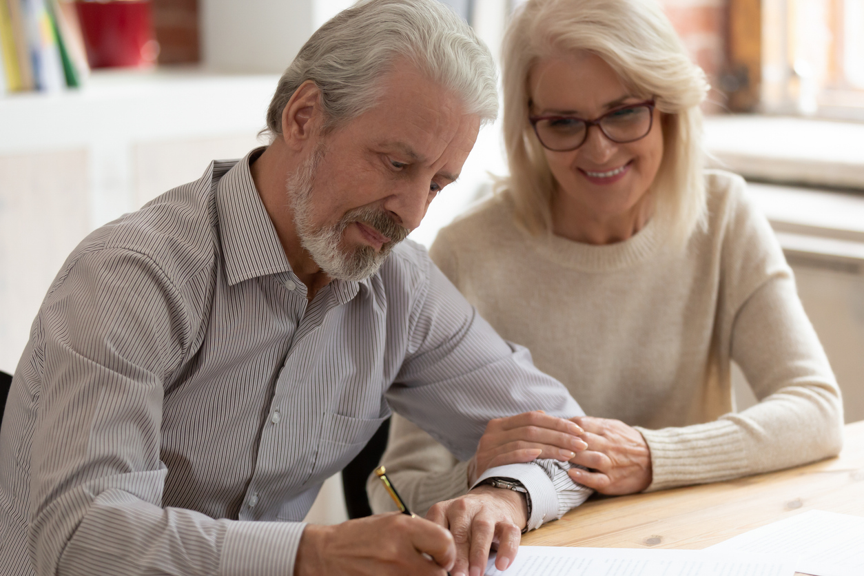 Happy older family couple husband and wife sign legal paper insurance contract write will testament, senior clients customers put signature on business document make financial deal
