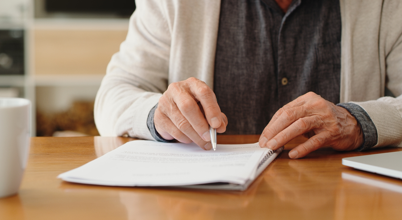 Hands of senior retirement woman writing a finance savings budget plan on paper or legal trust fund for after her funeral. Elderly person apply for pension or government financial support and help