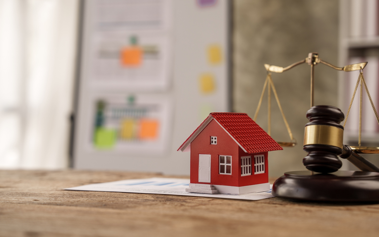scales of justice, gavel and small wooden toy house, working with documents, signing contract agreements. Real estate law concept.