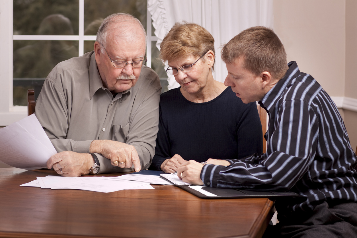 Financial advisor with senior couple going over paperwork