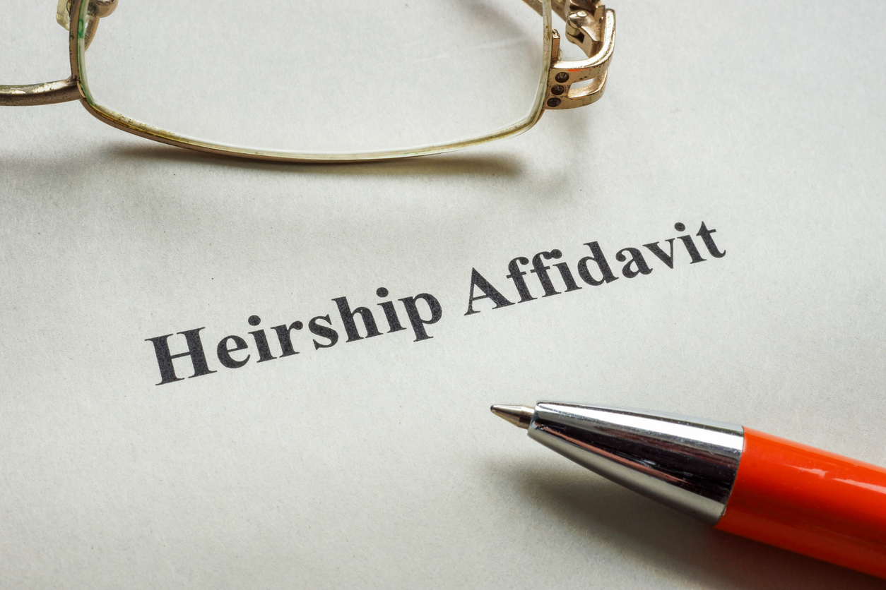 Document about heirship affidavit, glasses and a pen.