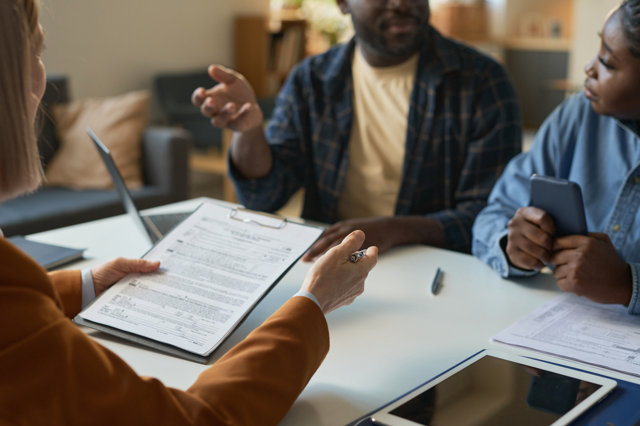 Close up of woman holding clipboard consulting family in attorney office