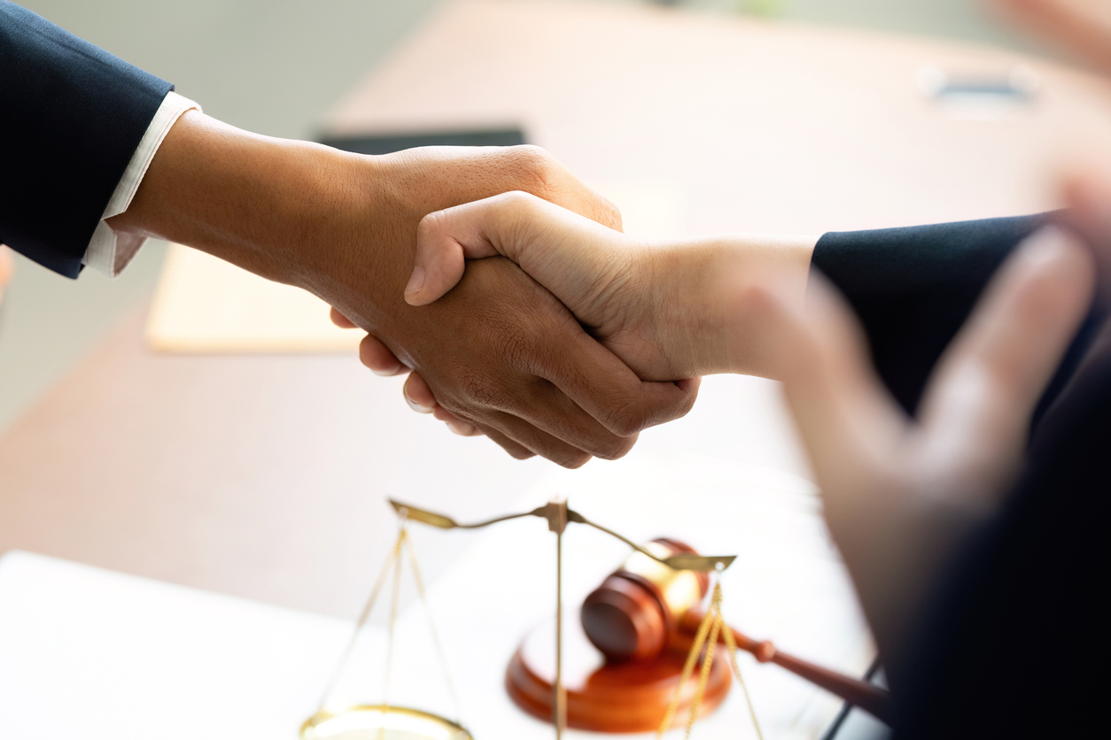 Two professionals shake hands to finalize an agreement, symbolizing trust and collaboration in a legal context.