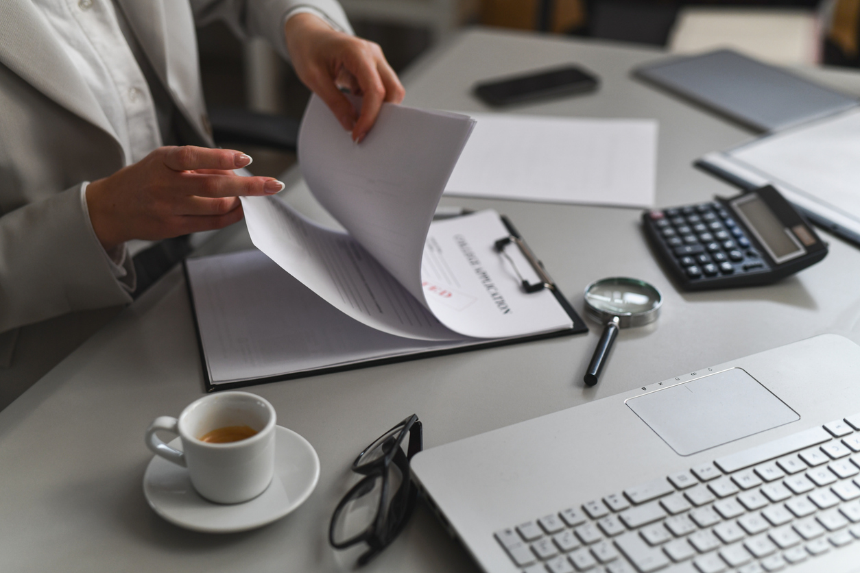 Close-up of hands arranging and sorting important business documents, highlighting order and organization in a professional setting.