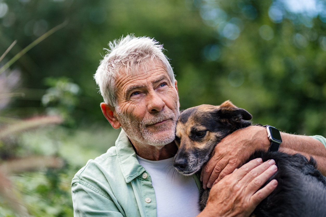 Senior man embracing loyal dog, relaxing outdoor moment
