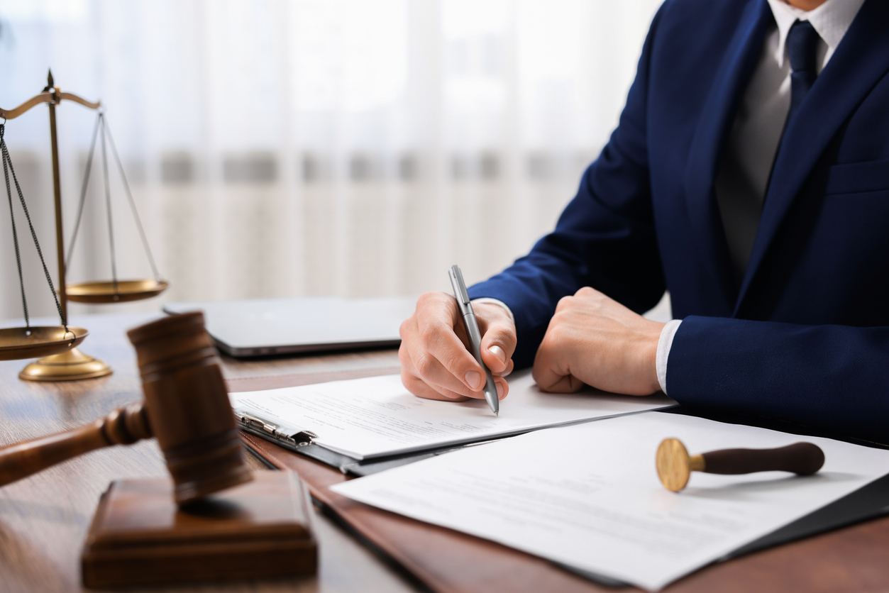 Notary signing document at table in office, closeup