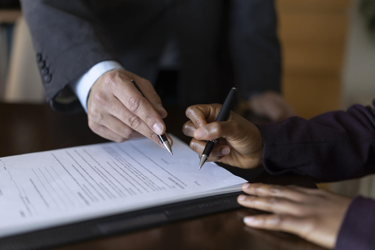 Close-up photo of business partners signing a contract, focusing on hands and pen as they complete the legal paperwork to solidify their partnership agreement