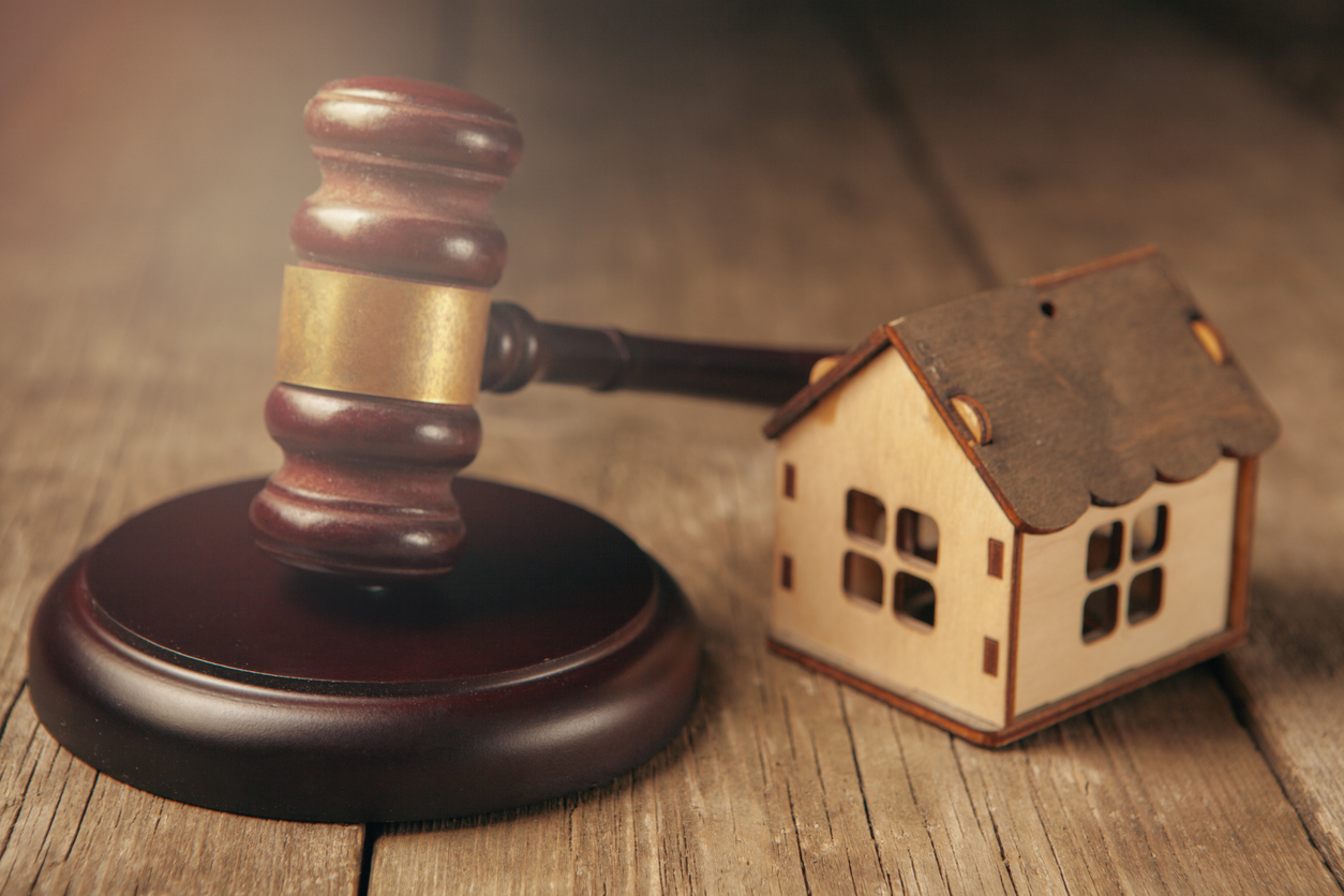 Wooden gavel and house on wooden background. Real estate concept
